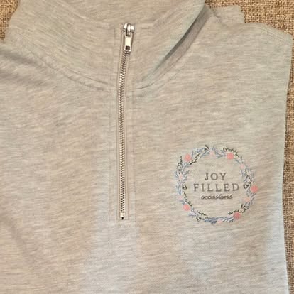 Grey 3/4-zip pullover embroidered with the Joy Filled Occasions floral-wreath logo