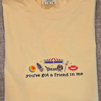Yellow tee with a colorful 'you've got a friend in me' embroidered design