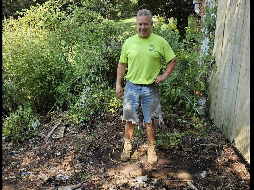 The same corner after Mary cleared it — bare ground and a customer standing where the pile was