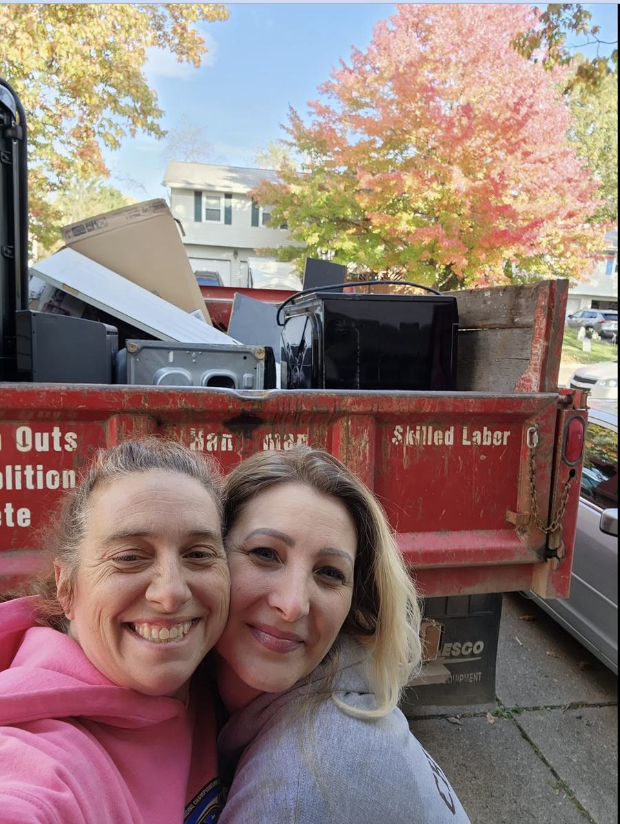 Mary and a customer cheek to cheek, smiling in front of the loaded red truck on an autumn street