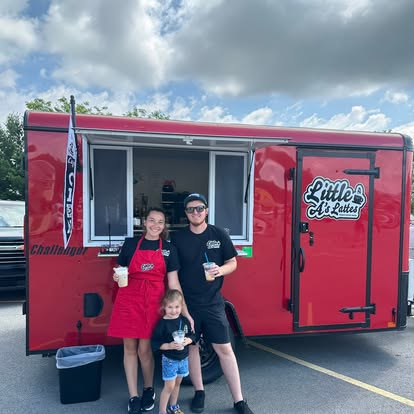 Little A's Lattes red coffee trailer with the team and a little girl out front on a sunny day