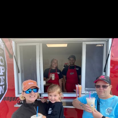 A mom and her little girl picking up iced drinks at the OPEN trailer window