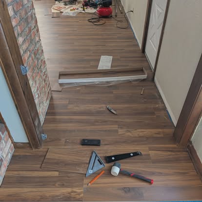 LVP flooring install in progress by brick wall
