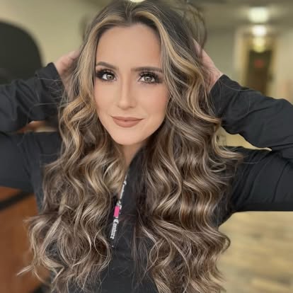 A Turning Heads client with long, dimensional honey-blonde balayage and soft curls